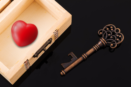 red heart inside opened wood treasure chest with vintage key の写真素材