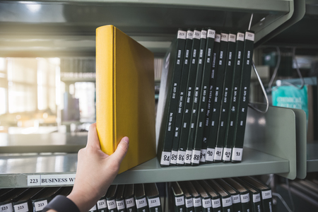 woman's hand taking book from shelf in libraryの写真素材
