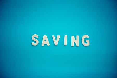 wooden alphabet word "saving" on blue backgroundの写真素材