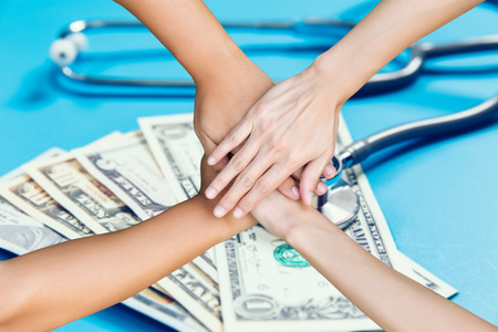 young people hands putting together on dollar and stethoscope backgroundの写真素材