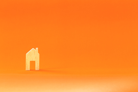 home shape wood on orange paper background, concepts for real estate and businessの写真素材