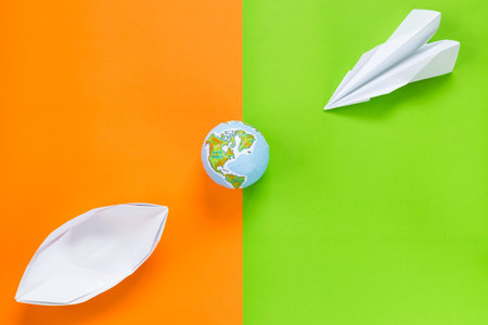 paper plane and boat with globe ball on colorful background, travel concept