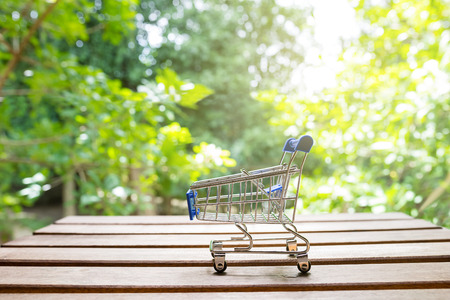 mini shopping cart on wood table with nature backgroundの写真素材