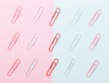 colorful paper clips arranged on half pink and blue backgroundの写真素材