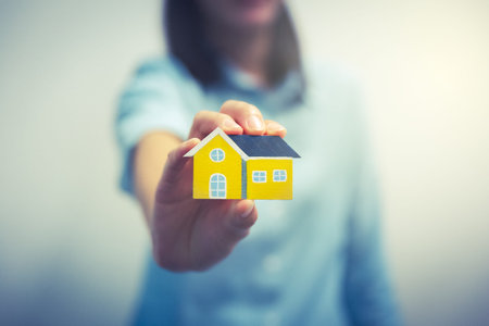 A woman's hand holding home shape wood model on hand