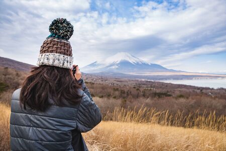 back of female traveler taking photo of Mount Fuji in winterの写真素材