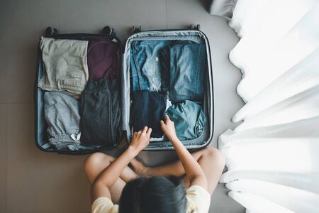 top view woman packing clothes in bag for traveling, vacation and tourism conceptの写真素材