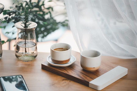 cup of hot coffee and tea on wood table besides windowの写真素材