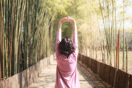 back of woman stretching among bamboo grove