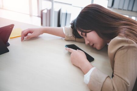 woman employee napping on desk with smart phone and tabletの写真素材