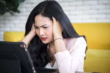 beautiful working woman sitting on floor with tablet on table with moody emotionalの写真素材