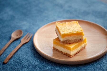 lemon cheese bar on wood plate with blue backgroundの写真素材