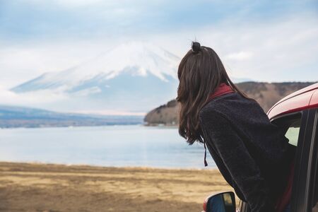 back of female traveler standing out from car looking at Mountain Fuji in winter, Lake Yamanakaの写真素材