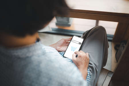 back view from woman using smartphone with shopping online searching screenの写真素材
