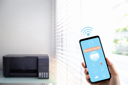 woman hand holding mobile phone showing smart home app screen with printer on background
