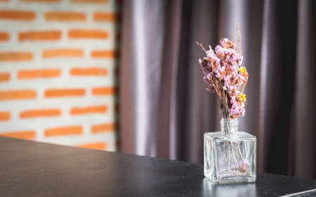 dried flower in glass bottle decorated on dusted wood table with brick wall and curtain backgroundの写真素材