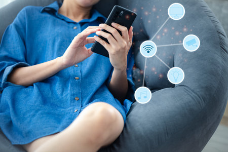 closeup woman with casual dress using mobile phone with smart home icon, home connection technology conceptの写真素材