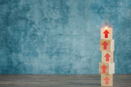 wooden cubes stack with red arrow up on blue background, grow progress for business conceptの写真素材