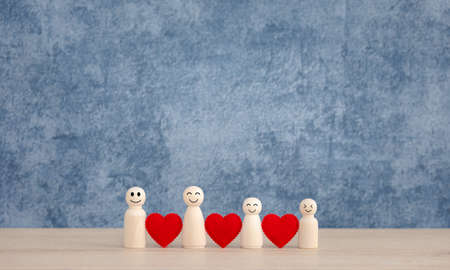 happy family wooden dolls with red heart on blue background, love in new normal conceptの写真素材