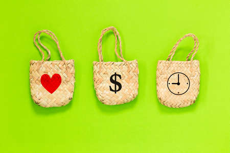 three bags with heart, dollar sign, and clock icon on green background, lifestyle planning and management for love, money, and time conceptの写真素材