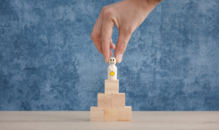 winner wood doll with gold medal on top of wooden cube stack, winning and successful conceptの写真素材