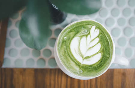 top view cup of green tea latte with latte art on wood tableの写真素材