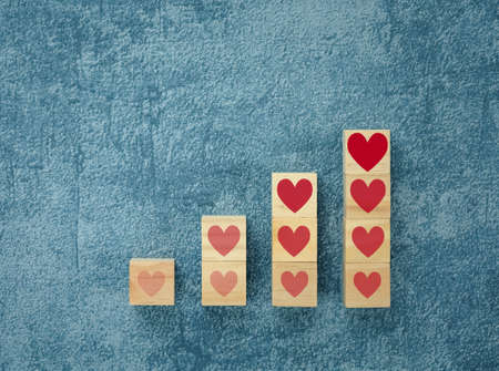 heart on wooden cubes arranged in bar graph shape on blue background, health conceptの写真素材