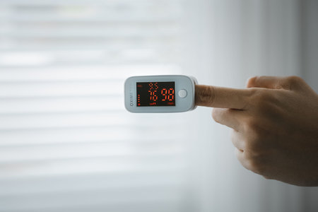 closeup woman's hand self monitoring her blood oxygen on oximeter, healthcare conceptの写真素材
