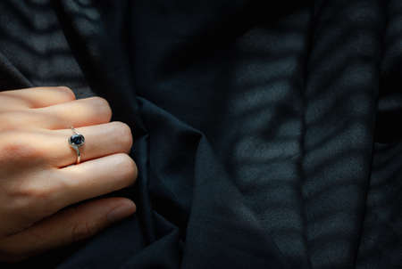 hand wearing white gold ring with blue sapphire on black background, fashion and design accessoryの写真素材