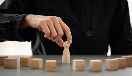 wooden doll among wood block with businesswoman on background, planning and strategy concept