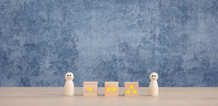 star rating on wooden cubes and emotional face on wooden dolls with blue background, satisfactory survey conceptの写真素材
