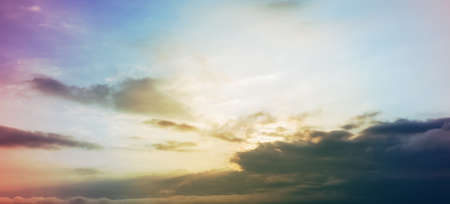 sun behind cloud with rays in pastel skyの写真素材