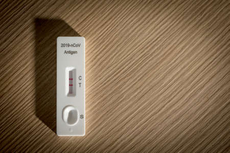 positive result of covid-19 self test kit on wood background, healtcare and medical conceptの写真素材