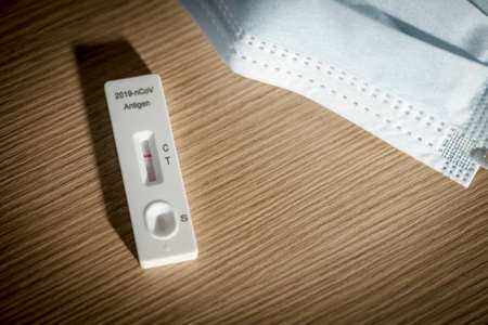 negative result of covid-19 self test kit with face mask on wood background, healtcare and medical conceptの写真素材