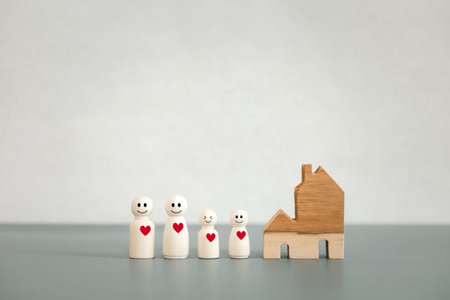 happy family wooden dolls with red heart and home model, warm family concept