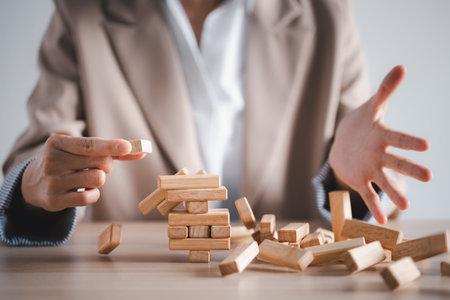 wooden block tower collapse with woman hand, business strategy concept