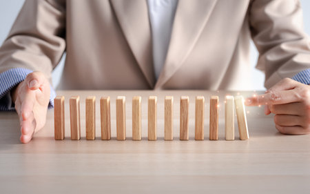 woman hand pushing domino with another hand blocking at the endの写真素材