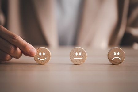 closeup businesswoman hand picking happy emotion face on wooden round piece arranged on table for...
