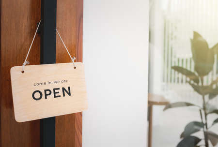 open sign hanging on wood door in front of shopの写真素材