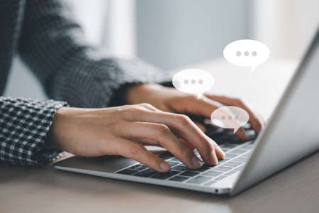 closeup woman hands typing on laptop with message icon as chatting on desk, wireless technology conceptの写真素材