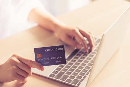 closeup woman hand holding credit card on hand and typing code on laptop, online payment concept