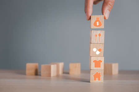 hand putting money bag wood cube arranging on four requisites cube stack, living conceptの写真素材
