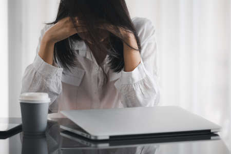 woman holding head by hands with hair covered, stressful on workingの写真素材