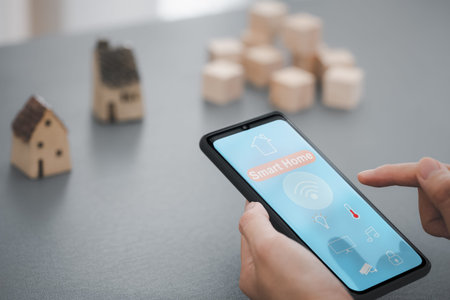 woman hand holding mobile phone showing smart home app screen with home model on background