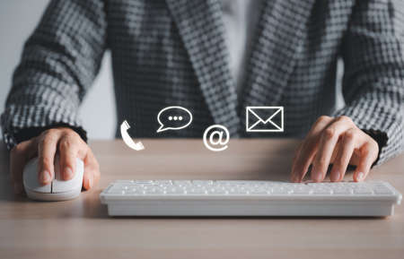 closeup woman using keyboard and mouse with phone, chat, address, mail icon above. customer service support conceptの写真素材