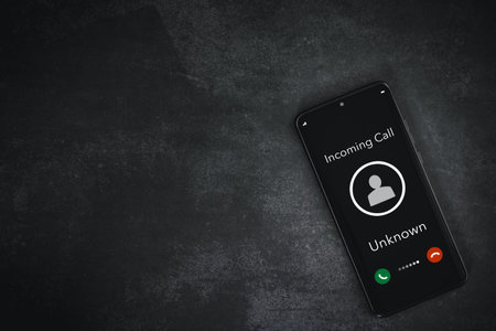 closeup smart phone screen with incoming call by unknown on rough grey background, technology and connecting conceptの写真素材