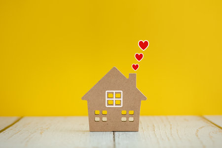 home sweet home, home model with red hearts above on yellow color backgroundの写真素材