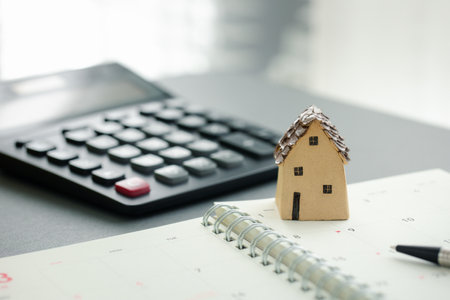 home budget calculation concept, home model on notebook with pen and calculatorの写真素材
