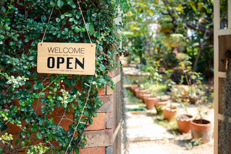 Open sign hanging in front of cafe with green garden backgroundの写真素材