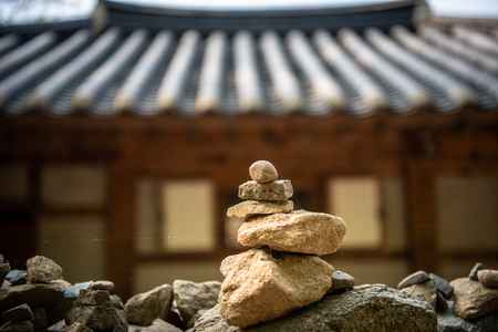 A stone tower in front of a traditional Korean houseの写真素材